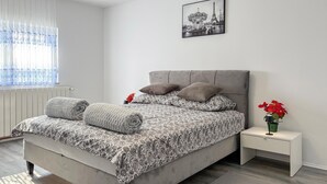 A bedroom with a bed, pillows, a nightstand, a vase with flowers, and a picture on the wall. - Stunning home in Salopeki Modruski with WiFi (Salopeki Modruski)