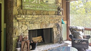 Una chimenea de piedra con un letrero que dice "FISH" y "Honest Weights". Hay una mesa de vidrio y una silla frente a la chimenea.