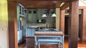 Una cocina con vigas de madera, una isla central y un horno empotrado.