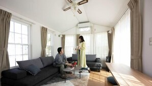 A modern living room with a sofa, a coffee table, a dining table, and a ceiling fan. - Inn the Fuji (Fujiyoshida)