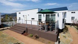 A white mobile home with a deck, outdoor seating, and a green awning. - Inn the Fuji (Fujiyoshida)
