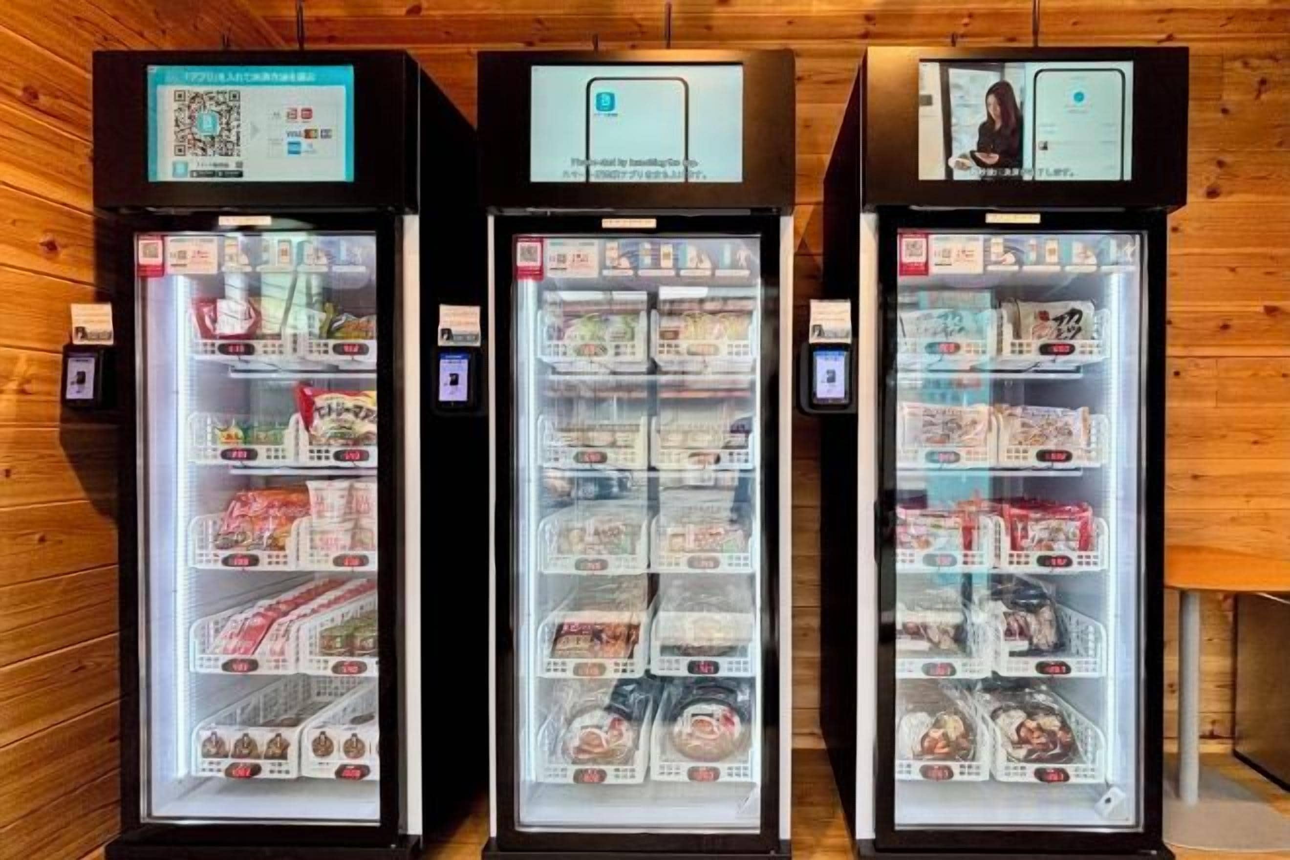 Three refrigerated display cases with various food items, each with a digital screen and a QR code.