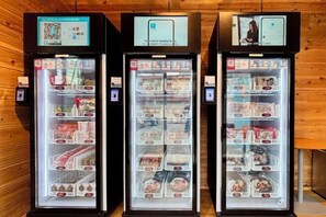 Three refrigerated display cases with various food items, each with a digital screen and a QR code. - Inn the Fuji (Fujiyoshida)