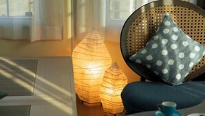 A room with a woven chair, a blue polka dot pillow, a small table with a blue cup and saucer, and two illuminated paper lanterns. - Inn the Fuji (Fujiyoshida)
