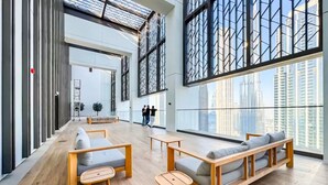 Eine geräumige Lobby mit Holzboden, einer Sofagarnitur und großen Fenstern mit Blick auf die Stadt.