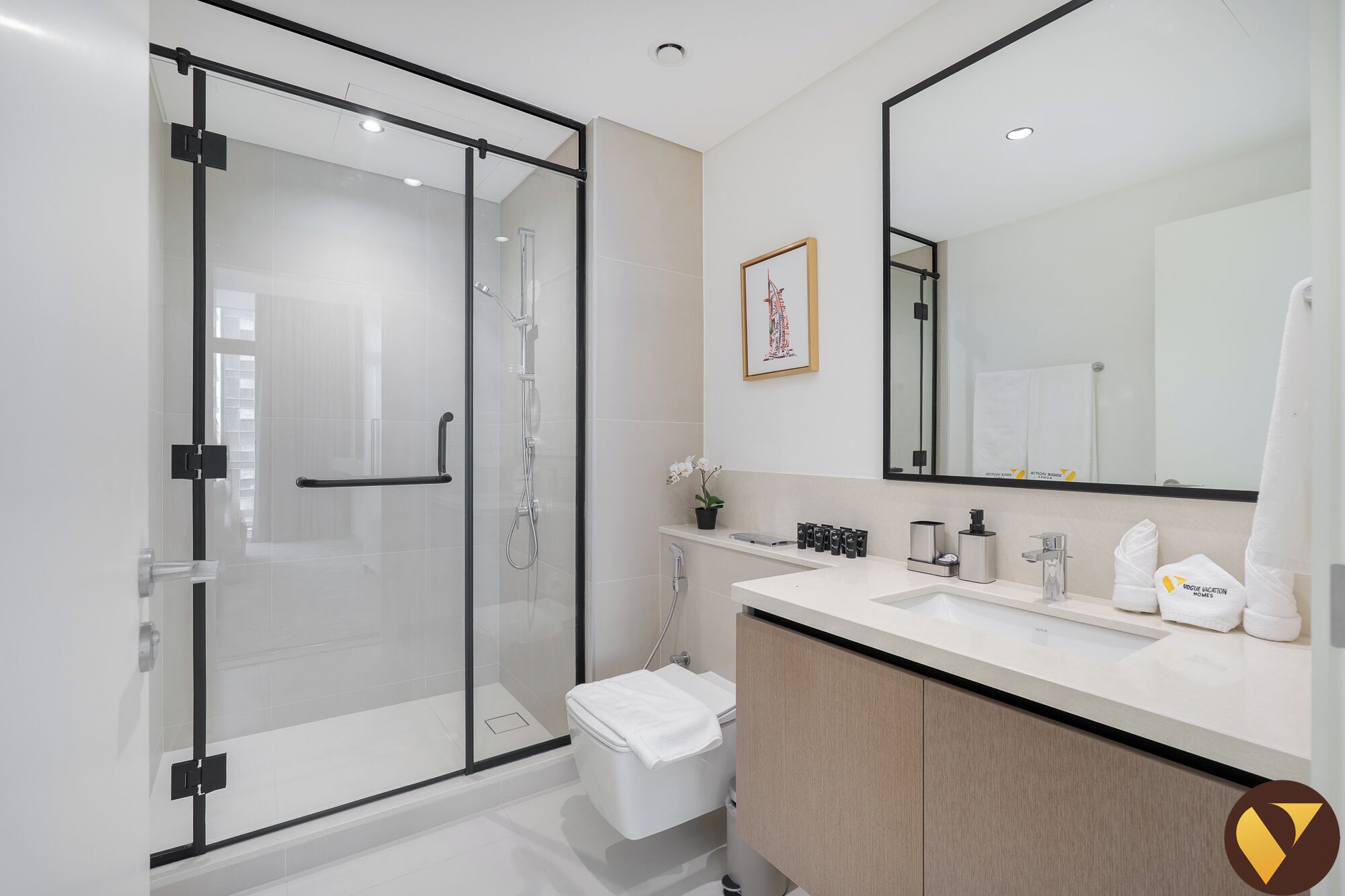 Een moderne badkamer met een douchecabine van glas, een witte wasbak en een grote spiegel.