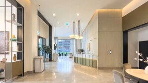 Eine moderne Hotelhalle mit poliertem Marmorboden, einer Rezeption, einer Sitzecke und großen Fenstern mit Blick auf die Stadtlandschaft.
