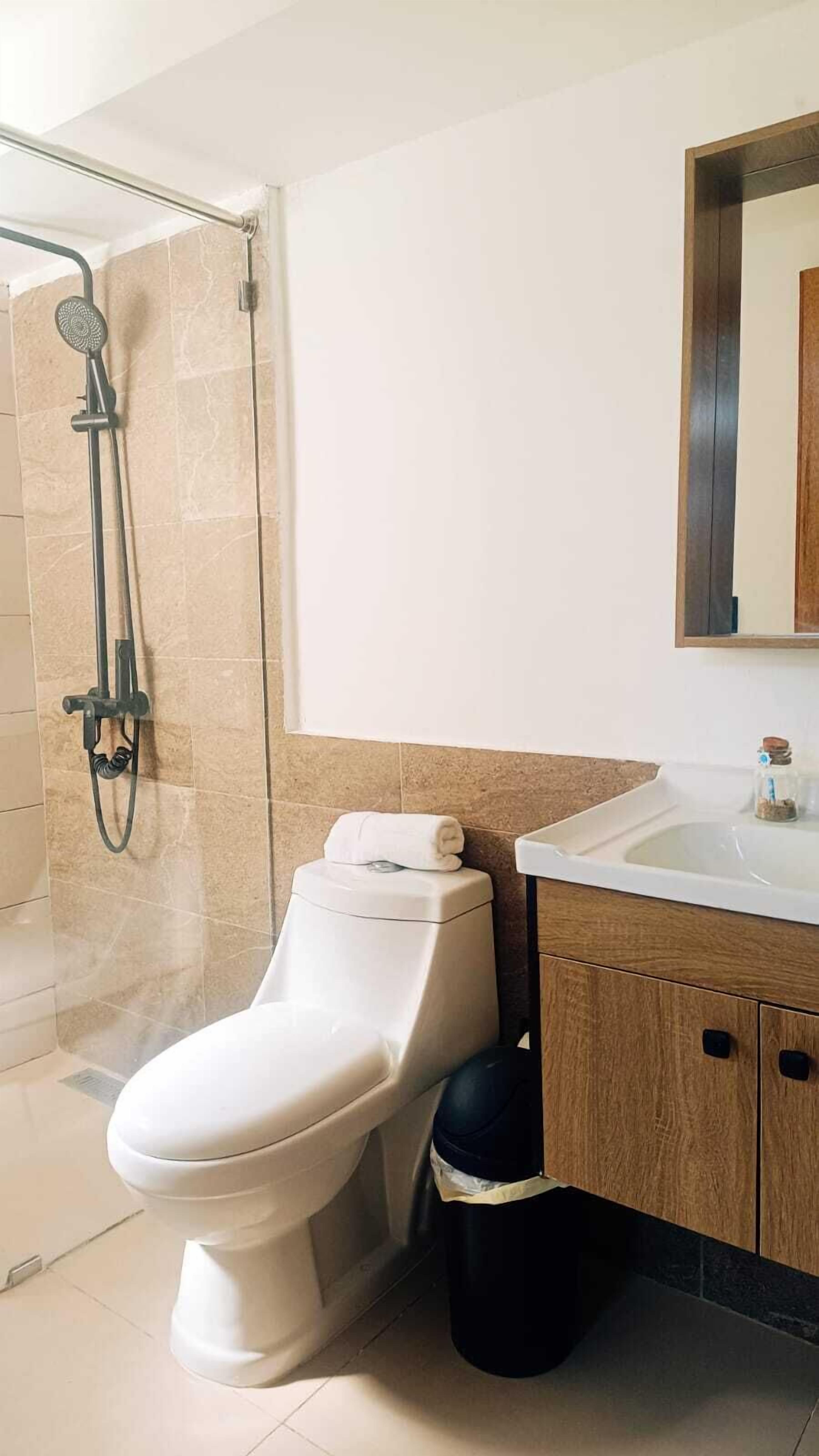 A modern bathroom with a toilet, shower, and sink.