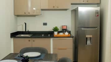 Una cucina moderna con mobili color beige, un frigorifero in acciaio inossidabile e un'area pranzo con un tavolo di legno apparecchiato per quattro persone.