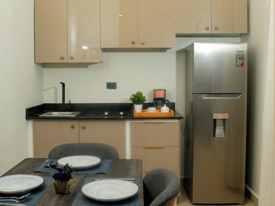 Una cucina moderna con mobili color beige, un frigorifero in acciaio inossidabile e un'area pranzo con un tavolo di legno apparecchiato per quattro persone.
