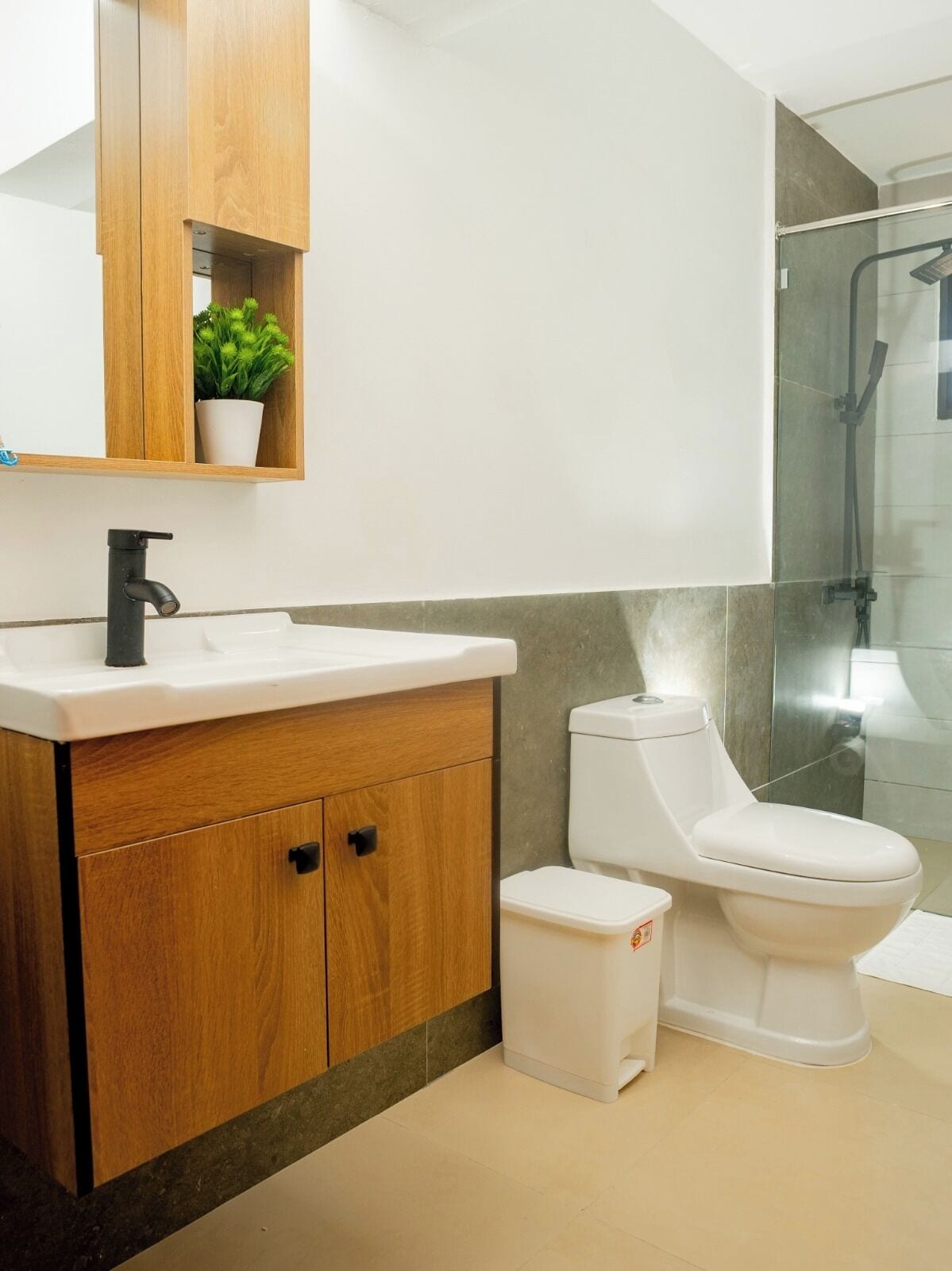 Un baño moderno con tocador de madera, lavamanos blanco y retrete.