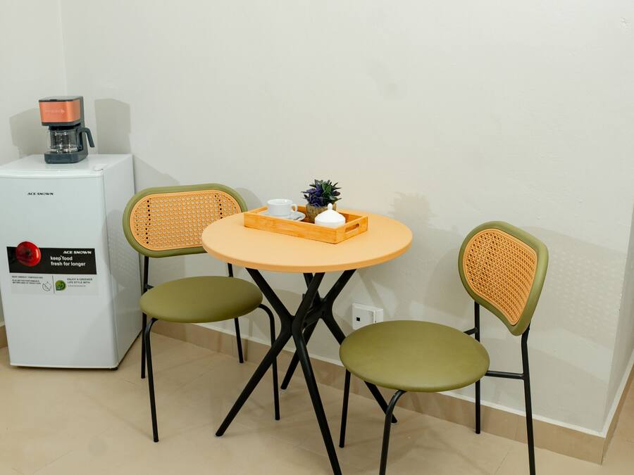 A small dining area with a round table, two chairs, and a coffee machine.