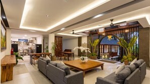 A modern living room with a sofa set, a wooden coffee table, and a dining area with chairs and a table. - Paripadi Studio Canggu (Bali)