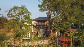 A two-story house with a balcony, surrounded by lush greenery and a small garden. - Paripadi Studio Canggu (Bali)