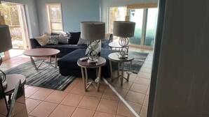 A living room with a sofa, two side tables with lamps, a coffee table, and a view through a glass door.