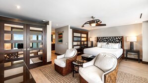 A modern hotel room with a large bed, two white armchairs, a small table, and a ceiling fan. - Luxury Oceanfront Panoramic Views, Private Sauna & Beach Access - Vrkcv (Kailua-Kona)