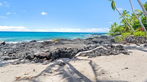 A rocky beach with clear blue water, palm trees, and a clear sky. - Luxury Oceanfront Panoramic Views, Private Sauna & Beach Access - Vrkcv (Kailua-Kona)