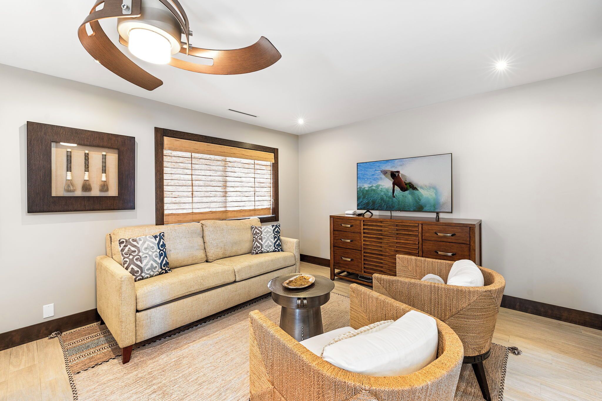 A modern living room with a sofa, wicker chairs, a coffee table, a TV, and artwork on the walls.