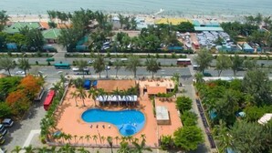 Luftaufnahme eines Resorts mit Schwimmbad, Zugang zum Strand und einem Parkplatz.