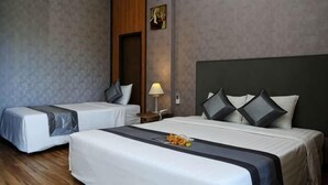 Ein Hotelzimmer mit zwei Betten, einem Holzkopfteil, einem Nachttisch mit Lampe und einem Bild an der Wand.
