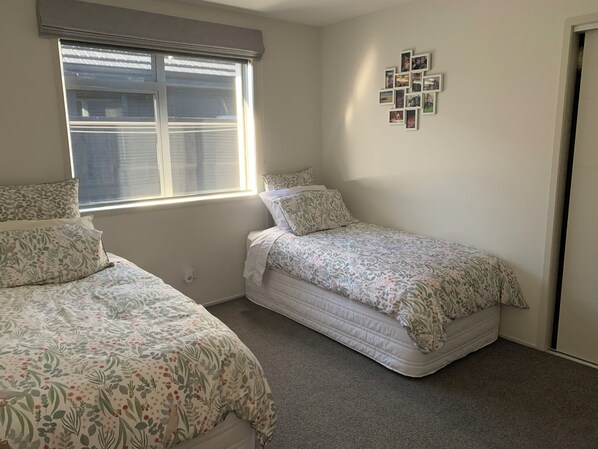 Un dormitorio con dos camas, una ventana y una colección de fotos en la pared.