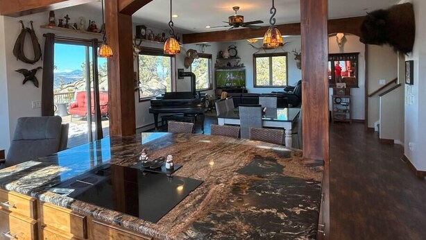 Un amplio salón con una isla grande, vigas de madera y un ventilador de techo.