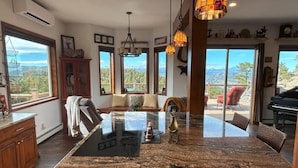 Una cocina amplia con una isla grande, ventanas panorámicas y un piano en el comedor.