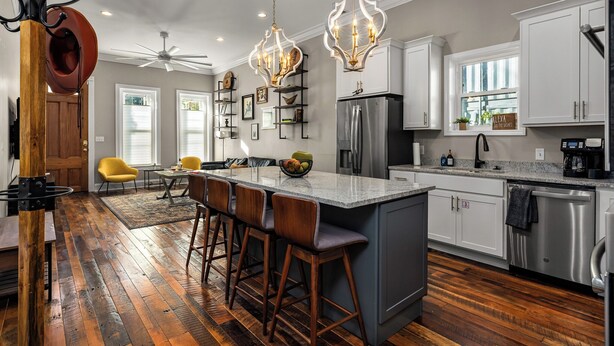 Una cocina moderna con una isla central, taburetes de bar, un refrigerador y una cafetera.