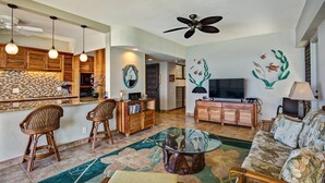 A modern living room with a kitchen, a dining area, and a TV. - Direct Ocean Front Steps From the Beach Large Lanai - Vrkcv (Kailua-Kona)