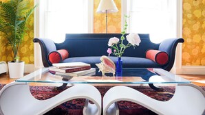 A modern living room with a blue sofa, a glass coffee table, and a potted plant. - The Waldoboro Inn Room 5 (Waldoboro)