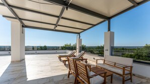 A covered outdoor seating area with wooden furniture and a view of the landscape. - Luxurious home in Kakma (Kakma)