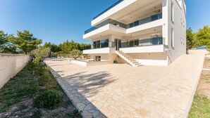 A modern multi-story house with a stone-paved courtyard, large windows, and a satellite dish. - Luxurious home in Kakma (Kakma)