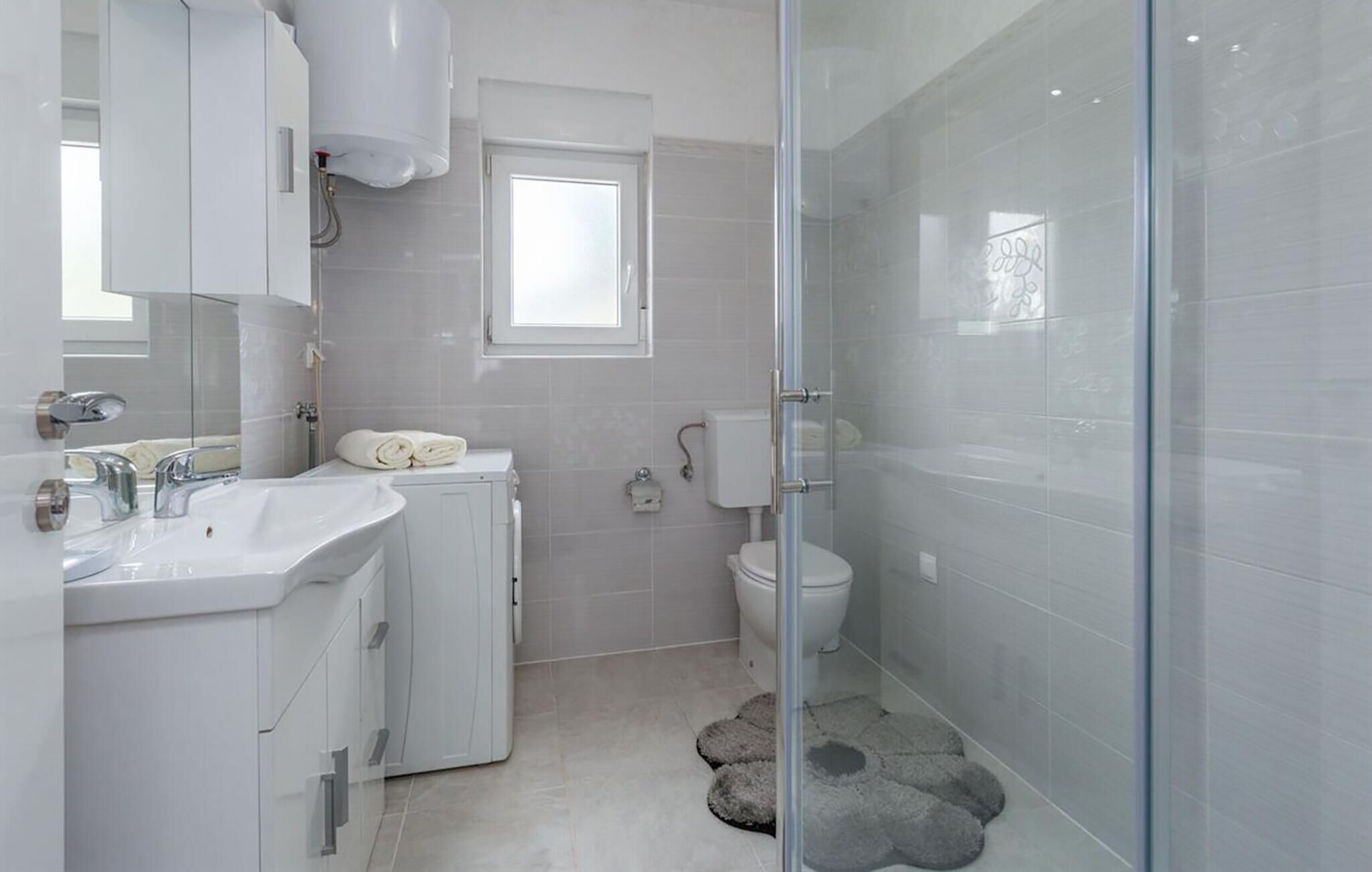 A modern bathroom with a glass shower enclosure, a white sink, and a toilet.