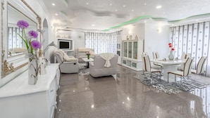 Una sala de estar moderna con un sofá, un televisor y un comedor con sillas y una mesa.