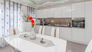 Una cocina moderna con armarios blancos, una mesa de comedor con sillas y un jarrón con flores.