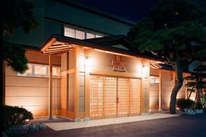 A traditional Japanese-style building with a wooden gate, a covered entrance, and a well-lit facade. - Ryokan Ichinomatsu (Hakodate)