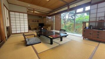 A traditional Japanese room with tatami flooring, a low table, chairs, and a sliding door.
