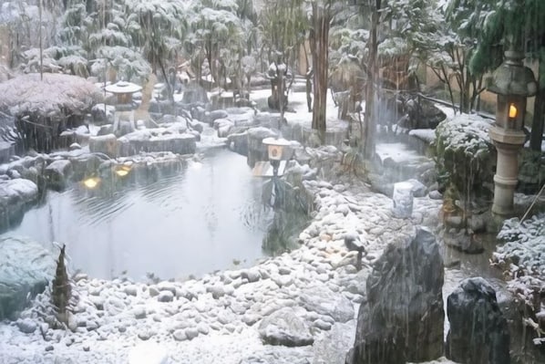 A serene pond with rocks and a lantern in a snowy garden. - Ryokan Ichinomatsu (Hakodate)