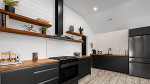 Una cocina moderna con armarios negros, encimeras de madera y baldosas blancas tipo metro.