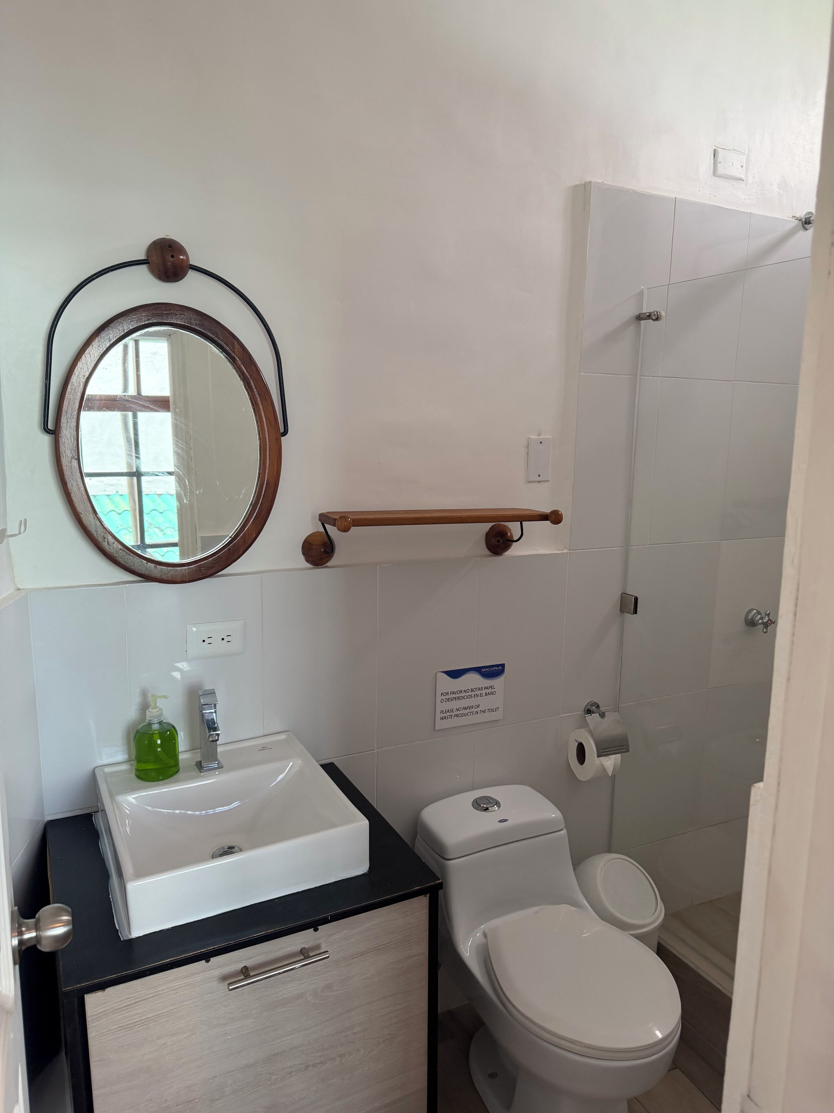 A bathroom with a sink, mirror, toilet, and shower.