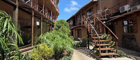 Un patio con un sendero central, rodeado de edificios con balcones y barandillas de madera.