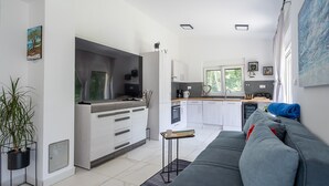 Une cuisine moderne avec des meubles blancs, un coin repas doté d’un canapé gris et une vue sur l’extérieur.