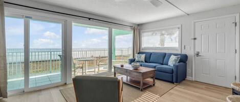 A spacious living room with a balcony, a ceiling fan, and a blue sofa.