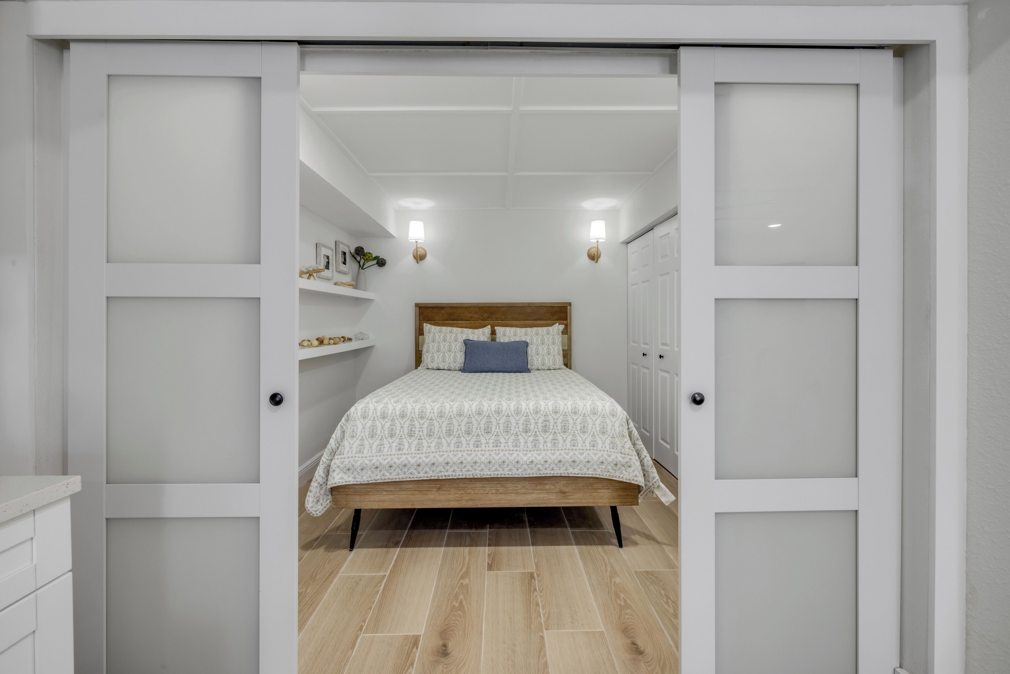 Une chambre à coucher avec un lit en bois, des murs blancs et un plafond blanc.