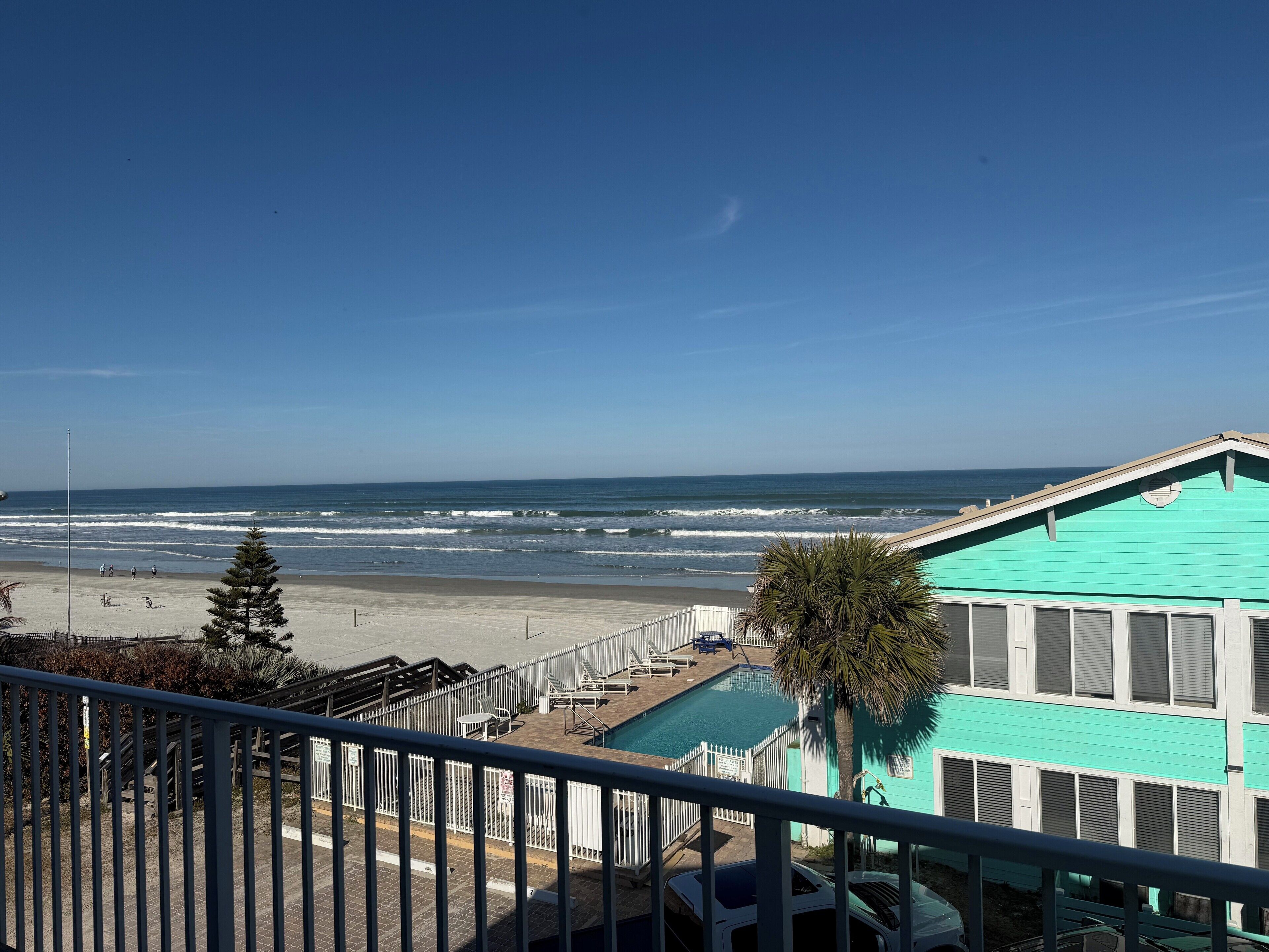 A view of a beach with a pool and a building with a turquoise roof.