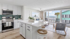 A modern kitchen with white cabinetry, a large island, and a view to a balcony.