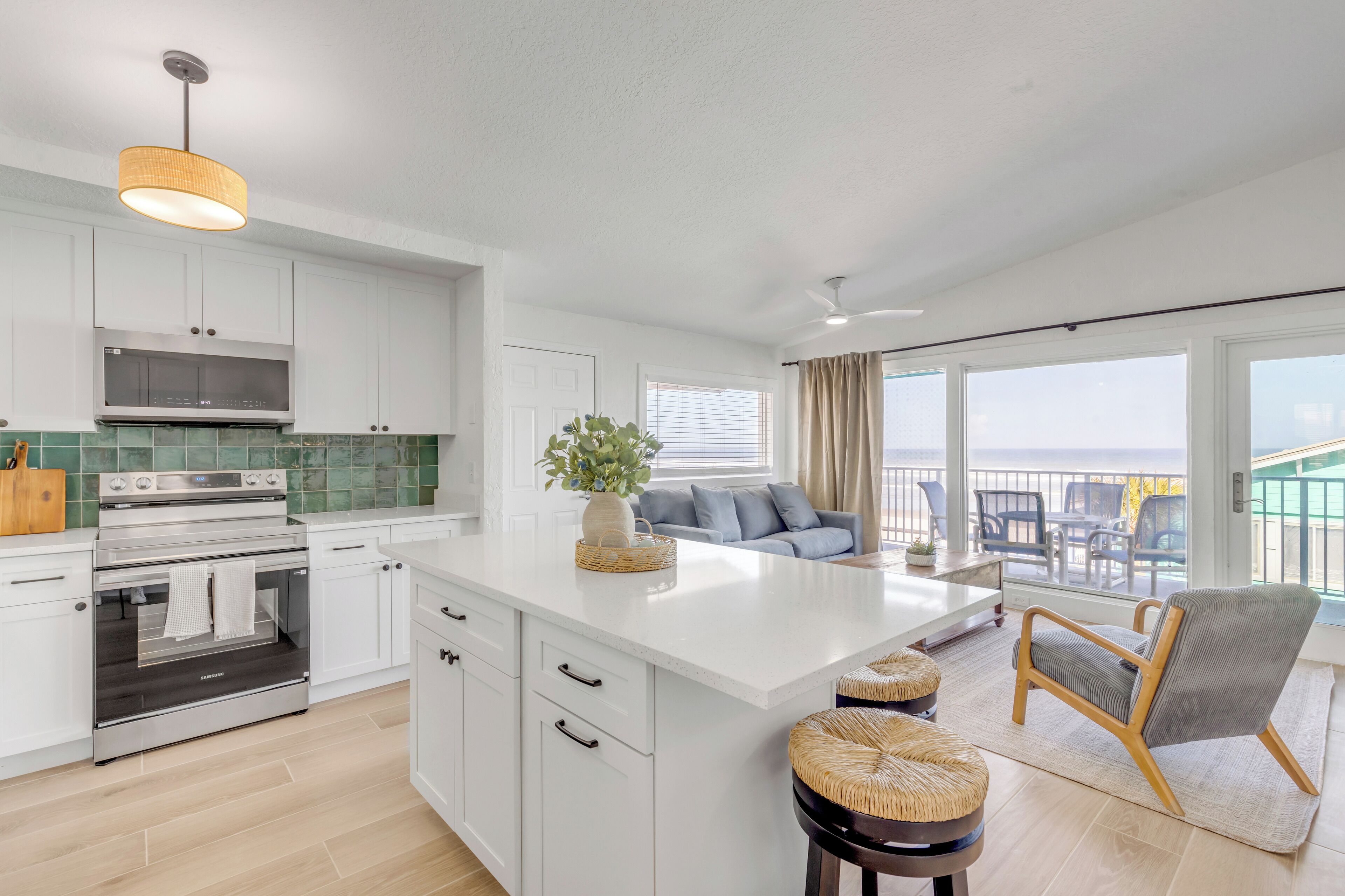 A modern kitchen with white cabinetry, a stainless steel oven, and a large island with stools.