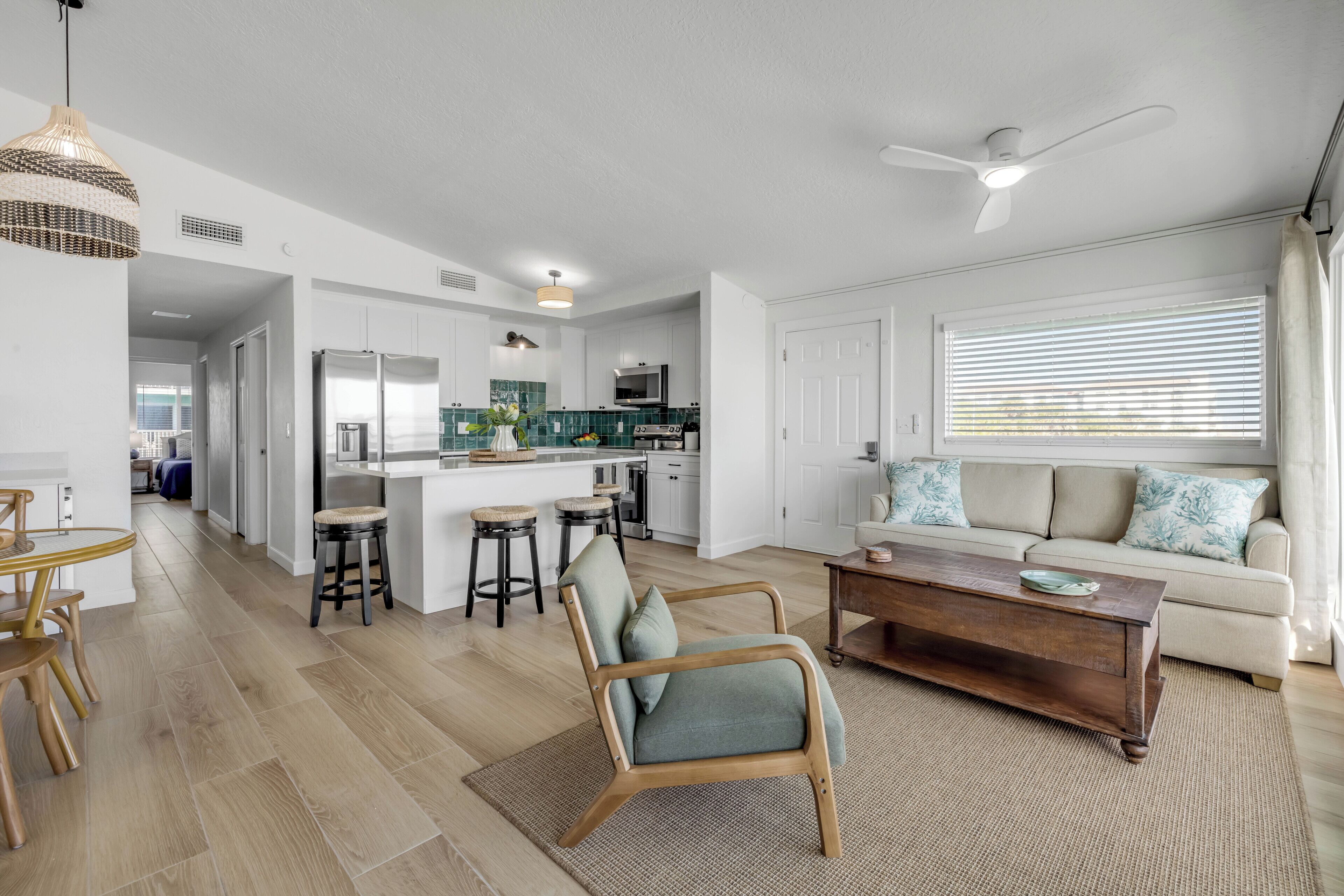 A modern kitchen with white cabinets, a central island, and a dining area with a wooden table and chairs.