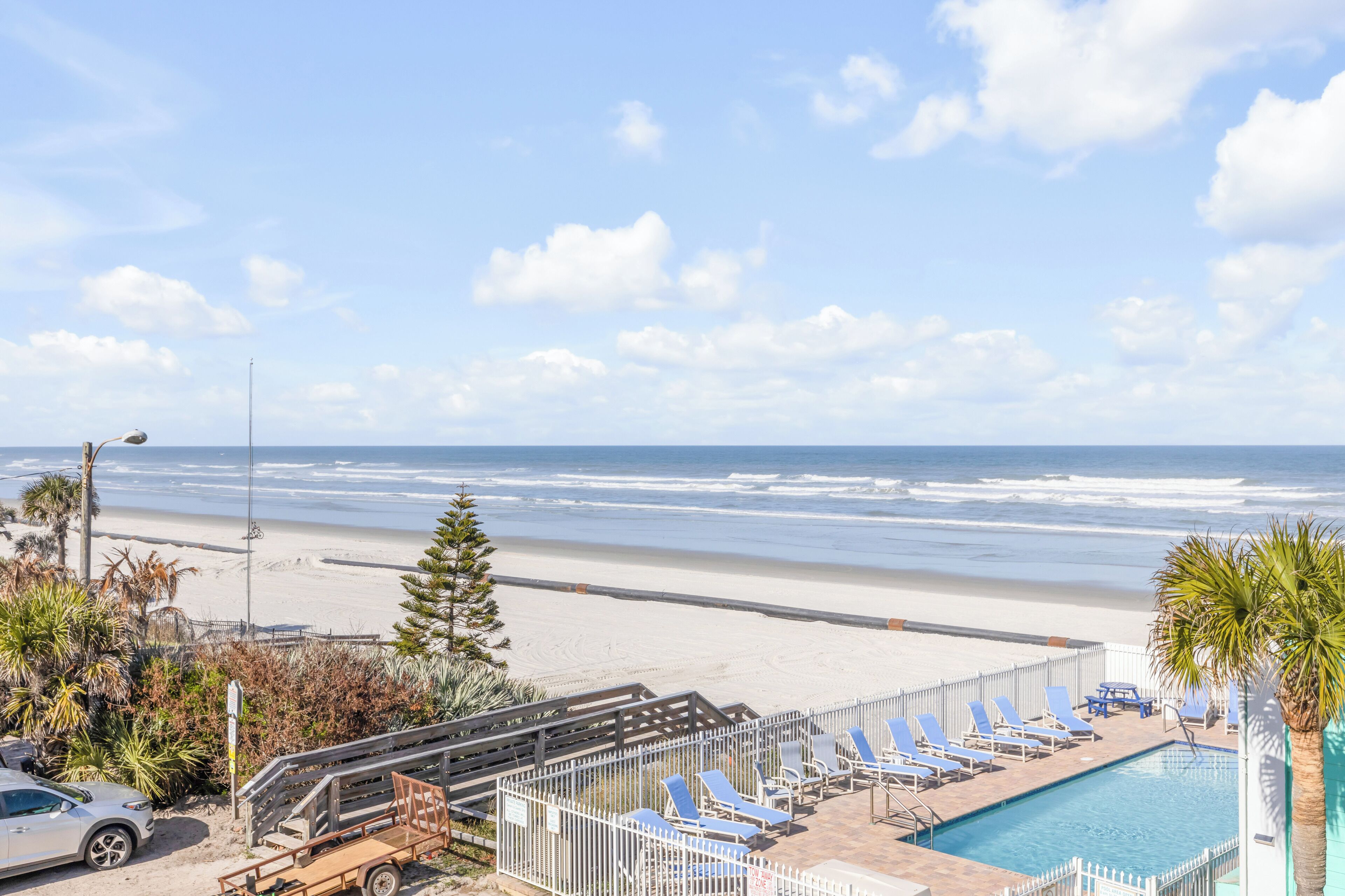 Une vue sur la plage avec une piscine et des chaises longues.