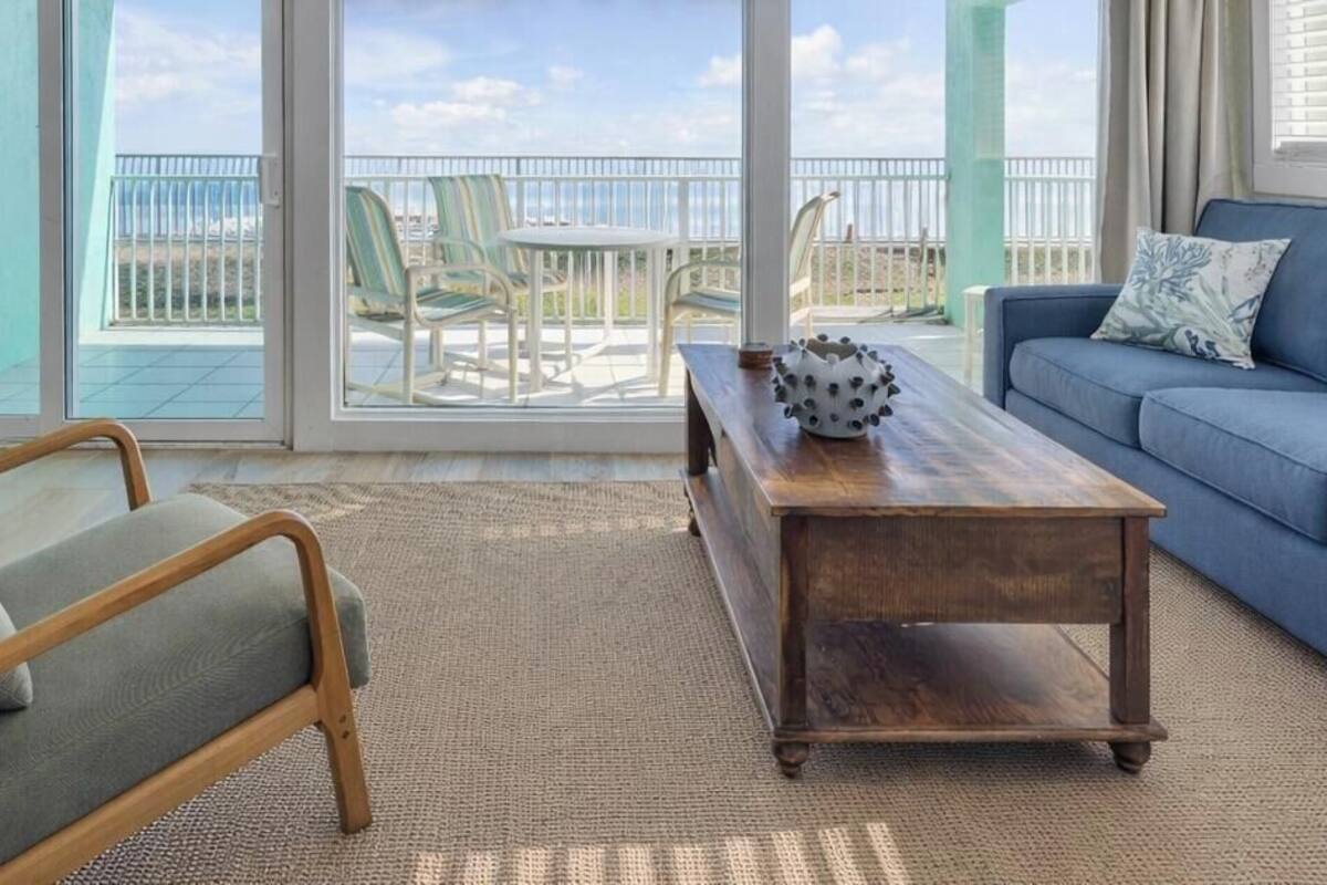 Uma sala de estar com um sofá azul, uma mesa de centro de madeira e uma poltrona verde.